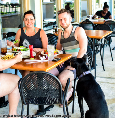Photo of couple eating outside with black dog